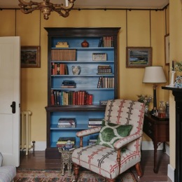 a room with a bookcase a chair and a lamp